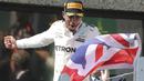 Pebalap F1 asal Inggris, Lewis Hamilton mengibarkan bendera negaranya usai menjuarai ajang Formula One Canadian Grand Prix di Montreal, Canada, (11/6/2017).  (Tom Boland/The Canadian Press via AP)