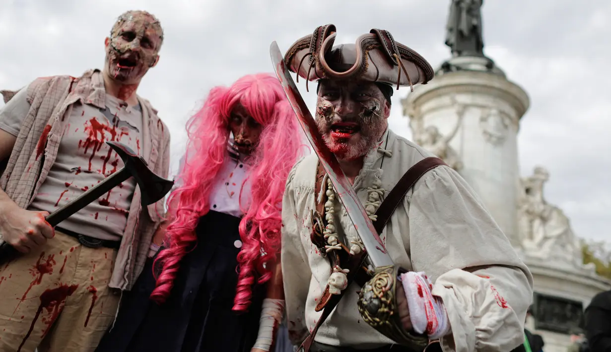 Tiga orang peserta mengenakan kostum zombie berpose saat mengikuti "Zombie Walk" di Paris, Prancis (7/10). Acara ini diadakan setiap tahun dan manjadi daya tarik untuk wisatawan. (AFP Photo/Thomas Samson)