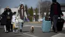 Seorang wanita berjalan dengan anjingnya setelah melintasi perbatasan dari Ukraina di perbatasan Rumania-Ukraina, di Siret, Rumania (25/2/2022). Ribuan orang Ukraina melarikan diri dari perang dengan melintasi perbatasan mereka ke barat untuk mencari keselamatan. (AP Photo/Alexandru Dobre)