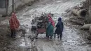 Anak-anak Kashmir mendorong gerobak berisi kayu bakar pada hari yang dingin di pinggiran Srinagar, Kashmir yang dikuasai India, Senin (27/12/2021). (AP Photo/Mukhtar Khan)