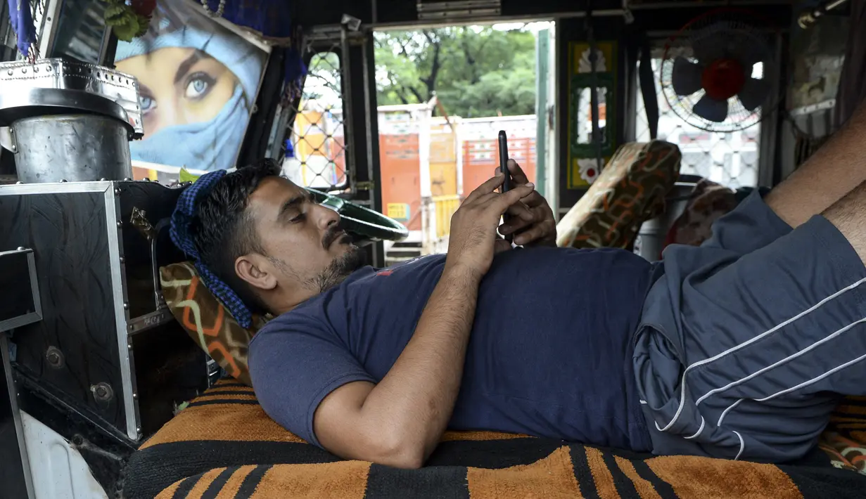 Seorang pria memeriksa ponselnya di sebuah truk yang diparkir di sebuah terminal di Chennai (19/9/2019). Semua asosiasi besar yang menjalankan truk, bus, mobil, tempo, taksi di Delhi dan Noida telah bergabung dalam protes satu hari ini. (AFP Photo/Arun Sankar)