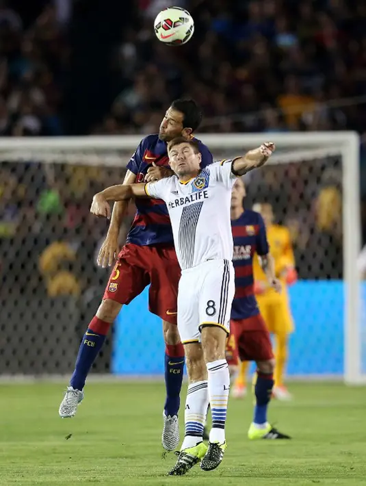 Gelandang LA Galaxy, Stevan Gerrard berebut bola udara dengan gelandang Barcelona, Sergio Busquets pada laga International Champions Cup 2015 di Rose Bowl, California, Rabu (22/7/2015). Barcelona menang 2-1 atas LA Galaxy. (AFP PHOTO/Stephen Dunn)