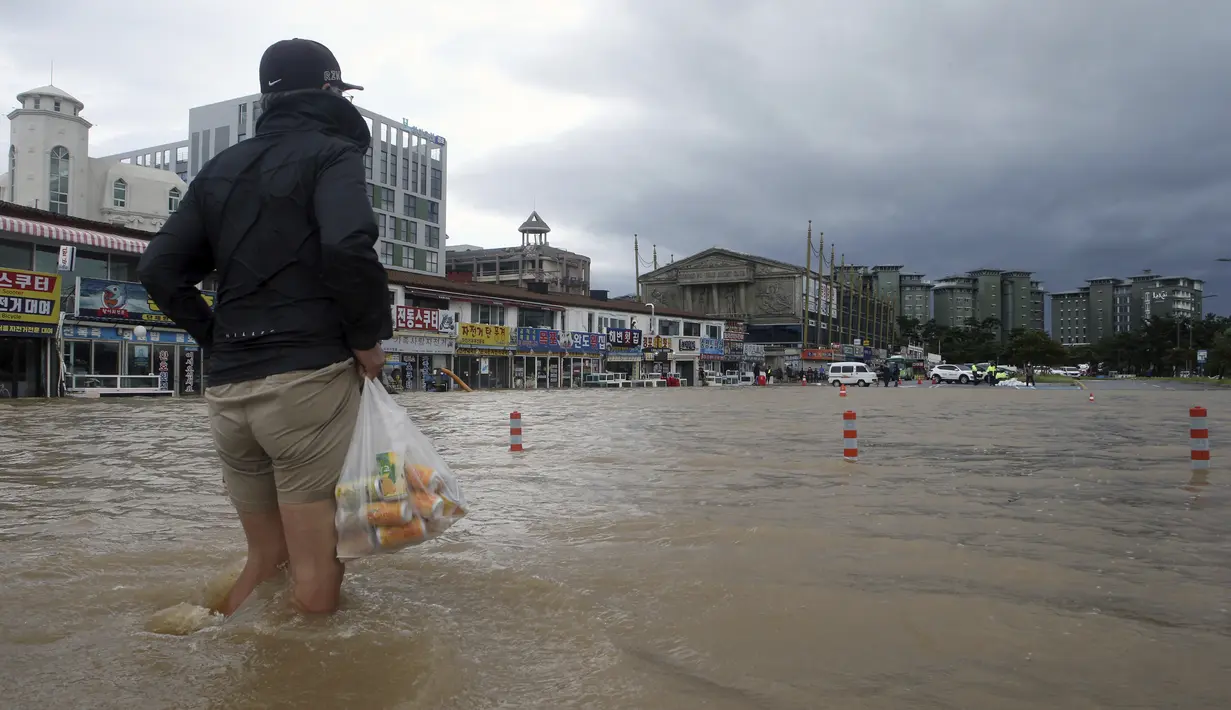 Seorang warga berjalan melewati banjir di Gangneung, Korea Selatan, Kamis (3/9/2020). Lebih dari 2.200 orang dievakuasi ke tempat penampungan sementara. (Lee Hae-yong/Yonhap via AP)