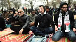 Warga Muslim mendengarkan ceramah saat menggelar Salat Jumat berjamaah di depan Gedung Putih, Jumat (8/12). Para warga muslim ini menggelar sajadah mereka di sebuah taman yang ada di depan kediaman resmi Presiden AS Donald Trump. (Eric BARADAT / AFP)