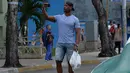 Seorang pria menggunakan ponselnya untuk terhubung ke internet melalui WiFi di Havana, Rabu (5/12). Hampir setengah dari 11,2 juta penduduk Kuba memiliki ponsel, namun tidak semua akan mampu membeli paket internet ponsel. (YAMIL LAGE/AFP)