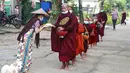 Biksu Buddha yang mengenakan masker menerima makanan dari umat saat mereka mengumpulkan sedekah pagi di Yangon, Myanmar, Kamis (15/7/2021). Myanmar melaporkan kasus pertama Covid-19 pada Maret 2020 dan gelombang kedua virus corona terjadi pada Agustus 2020. (AP Photo/Thein Zaw)