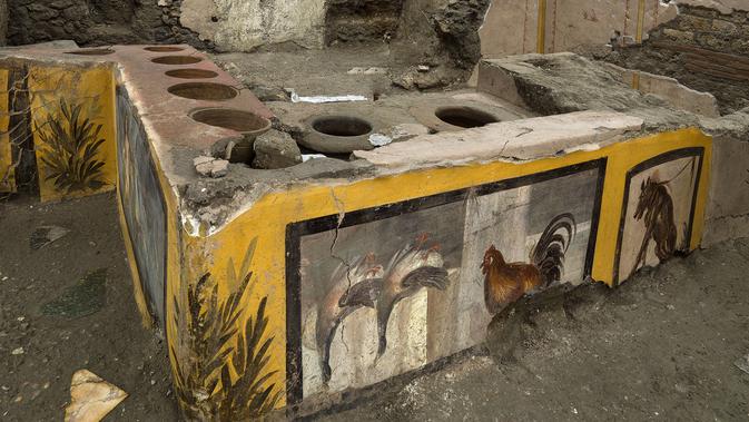 Foto yang dirilis pada 26 Desember 2020 terlihat konter makanan dan minuman panas di Pompeii, Italia. Jejak kedai makanan berusia hampir 2.000 tahun ini berupa beberapa wadah tembikar yang ditanam di dalam meja dengan lubang melingkar. (Luigi Spina/Parco Archeologico di Pompei via AP)
