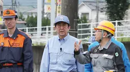 PM Jepang Shinzo Abe memeriksa daerah yang terkena dampak banjir dan longsor di Hita, prefektur Oita, Rabu (12/7). Tanah longsor dan banjir yang terjadi memicu evakuasi lebih dari 400 ribu orang meninggalkan rumah. (Nozomi Endo/Kyodo News via AP)