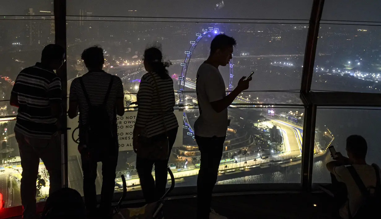 Turis melihat Sirkuit Marina Bay Street yang diselimuti kabut asap di Singapura (18/9/2019). Kabut asap dari kebakaran hutan yang terjadi di Sumatra dan Kalimantan membuat kelangsungan GP Singapura 2019 diliputi ketidakpastian. (AFP Photo/Mladen Antonov)