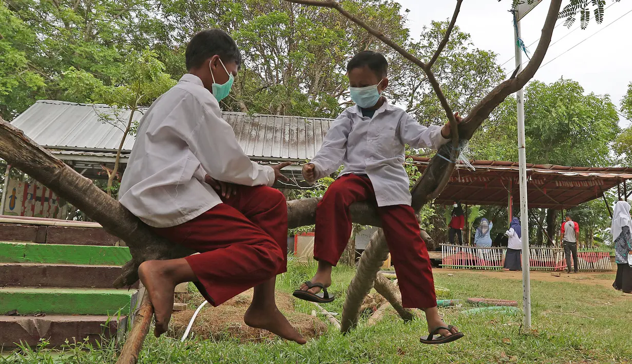 Dua murid SD bermain di atas pohon di sekolah alam Sukawangi, Kabuapaten Bekasi, Jawa Barat, Senin (30/11/2020). Kegiatan bermain di alam terbuka menjadi solusi bagi para murid untuk menghilangkan rasa jenuh usai belajar dimasa pandemi COVID-19. (Liputan6.com/Herman Zakharia)