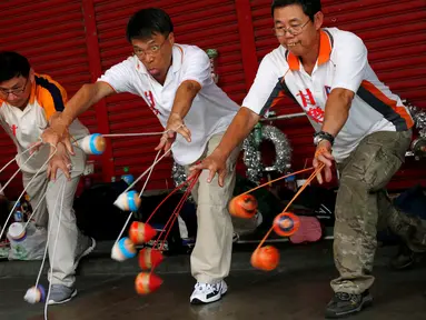 Sekelompok pakar gasing memainkan 18 gasing sekaligus saat turnamen gasing di New Taipei City, Taiwan (9/5). Dalam turnamen ini peserta menampilkan sejumlah trik mengagumkan. (REUTERS/Tyrone Siu)