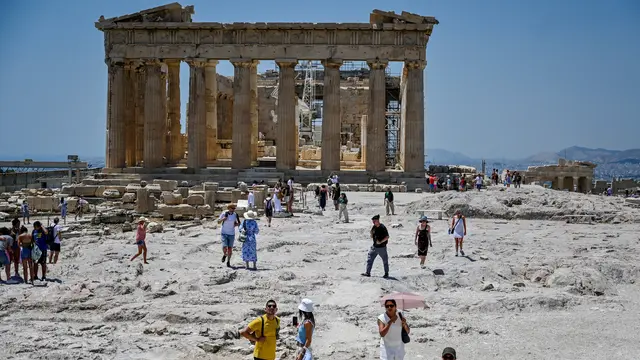 Wisatawan mengunjungi Acropolis di Athena, Yunani, Minggu (24/7/2022). (AFP/Louisa Gouliamaki)