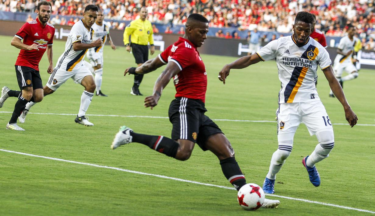 Pemain Manchester United, Antonio Valencia (kiri) mencoba melewati adanngan pemain LA Galaxy pada laga persahabatan di StubHub Center, California, Sabtu (15/7/2017). MU menang 5-2. (AFP/Ringo Chiu)