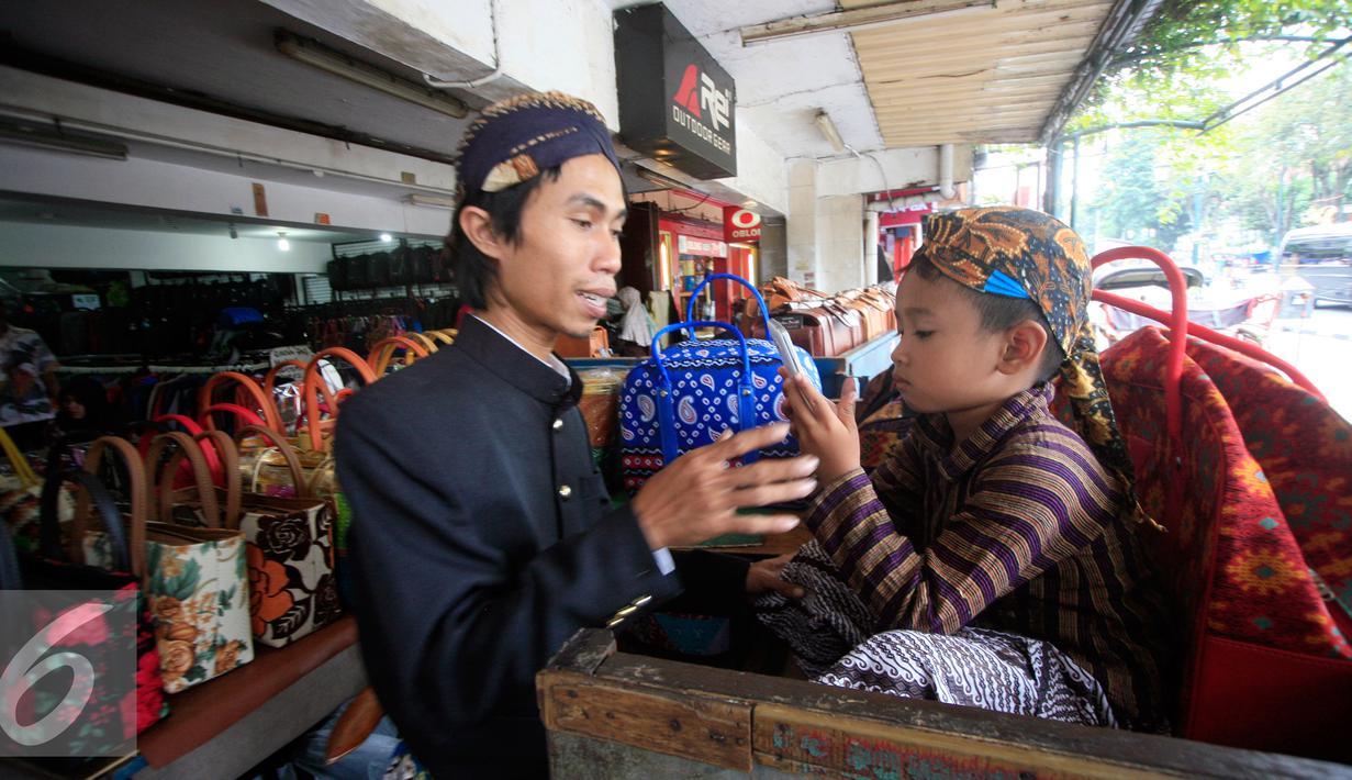 PKL bermain dengan seorang anak di emperan toko kawasan Malioboro mengenakan pakaian tradisional, Rabu (20/4/2016). Sejumlah PKL mengenakan pakain adat jawa menyambut hari Kartini 21 April besok. (Liputan6.com/Boy Harjanto)
