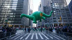 Balon Dino melayang di atas kawasan Sixth Avenue selama Parade Macy's Thanksgiving Day di New York, Kamis (22/11). Balon raksasa berbentuk ikon-ikon kartun terkenal menghiasi gelaran yang digelar untuk ke-92 tersebut. (Don EMMERT / AFP)