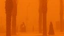 <p>Perempuan berjalan di tengah badai debu parah di Kota Kuwait pada 23 Mei 2022. Gumpalan debu besar yang melayang di atas Kuwait telah mengurangi visibilitas menjadi hampir nol di jalan-jalan hampir sepanjang hari di seluruh negeri. (Yasser Al-Zayyat / AFP)</p>