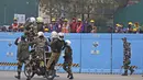 Pekerja menyaksikan pasukan pertahanan berlatih untuk parade Hari Republik mendatang di perbukitan Raisina, pusat kekuasaan pemerintah, di New Delhi, India (17/1/2022). India akan merayakan Hari Republik pada 26 Januari. (AP Photo/Manish Swarup)