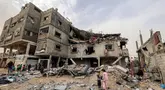 Anak-anak berdiri di luar gedung keluarga Sabah yang terkena serangan udara Israel di Deir el-Balah, Jalur Gaza tengah pada 8 April 2025. (Eyad BABA/AFP)