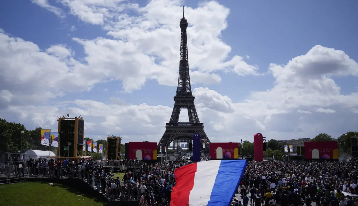 <p>Seorang pria mengibarkan bendera Prancis di zona penggemar Olimpiade di Trocadero Gardens di depan Menara Eiffel di Paris, Minggu (8/8/2021). Pelepasan tongkat tuan rumah akan dibagi antara Stadion Olimpiade di Tokyo dan pesta publik dan konser di Paris. (AP Photo/Francois Mori)</p>