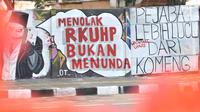 Mural bertulis 'Menolak RKUHP Bukan Menunda' terpampang pada dinding di Jalan Pemuda, Rawamangun, Jakarta, Selasa (1/10/2019). Mural tersebut respons dari seniman Jakarta terhadap RUU KUHP yang dinilai mencederai tatanan demokrasi. (merdeka.com/Iqbal Nugroho)