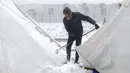 Seorang imigran membersihkan salju dari tenda darurat di Kamp Lipa, luar Bihac, Bosnia, Jumat (8/1/2021). Cuaca bersalju dan musim dingin telah membawa lebih banyak penderitaan bagi ratusan imigran yang terjebak selama berhari-hari di kamp tersebut. (AP Photo/Kemal Softic)
