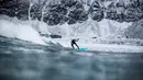 Seorang surfer menaiki papanya berselancar di melewati ombak di Unstad, Norwegia Utara (10/3). Peselancar ini menaklukan ombak dengan konidisi suhu minus 13 derajat Celsius. (AFP Photo/Olivier Morin)