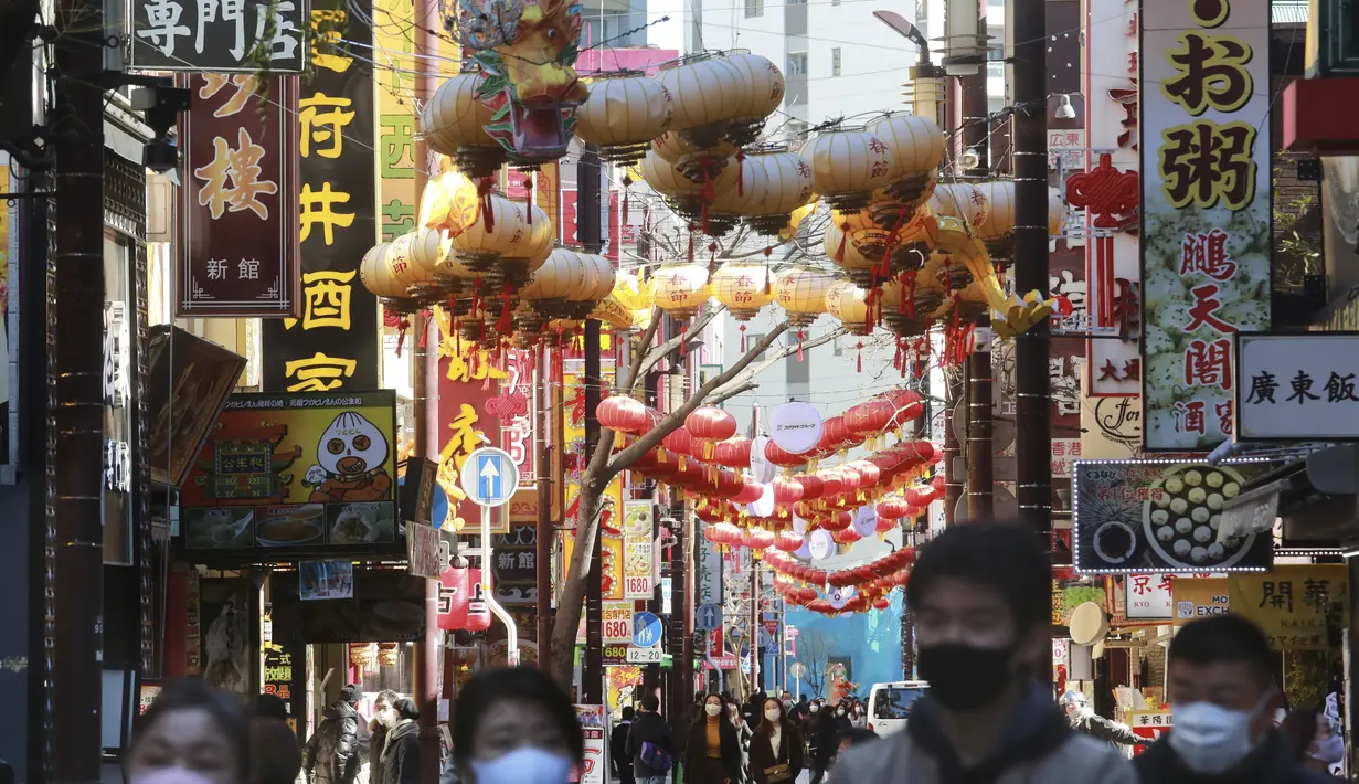 Orang-orang yang memakai masker berjalan di bawah pernak-pernik Imlek saat melintasi Chinatown di Yokohama, Prefektur Kanagawa, dekat Tokyo, Selasa (9/2/2021). Yokohama Chinatown adalah kawasan pecinan terbesar di Jepang, terletak di pusat kota Yokohama. (AP Photo/Koji Sasahara)