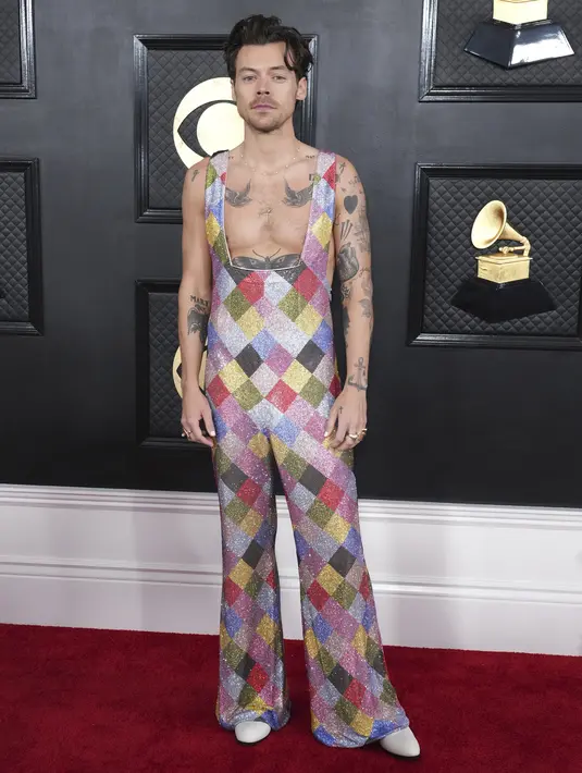Penyanyi-penulis lagu Inggris, Harry Styles berpose di red carpet saat tiba untuk ajang Grammy Awards 2023 di Crypto.com Arena, Los Angeles, AS, Minggu Malam (6/2/2023) waktu setempat. Sebagai aksesori, pelantun Adore You ini  memilih kalung dan cincin emas dengan sepatu putih. (Photo by Jordan Strauss/Invision/AP)