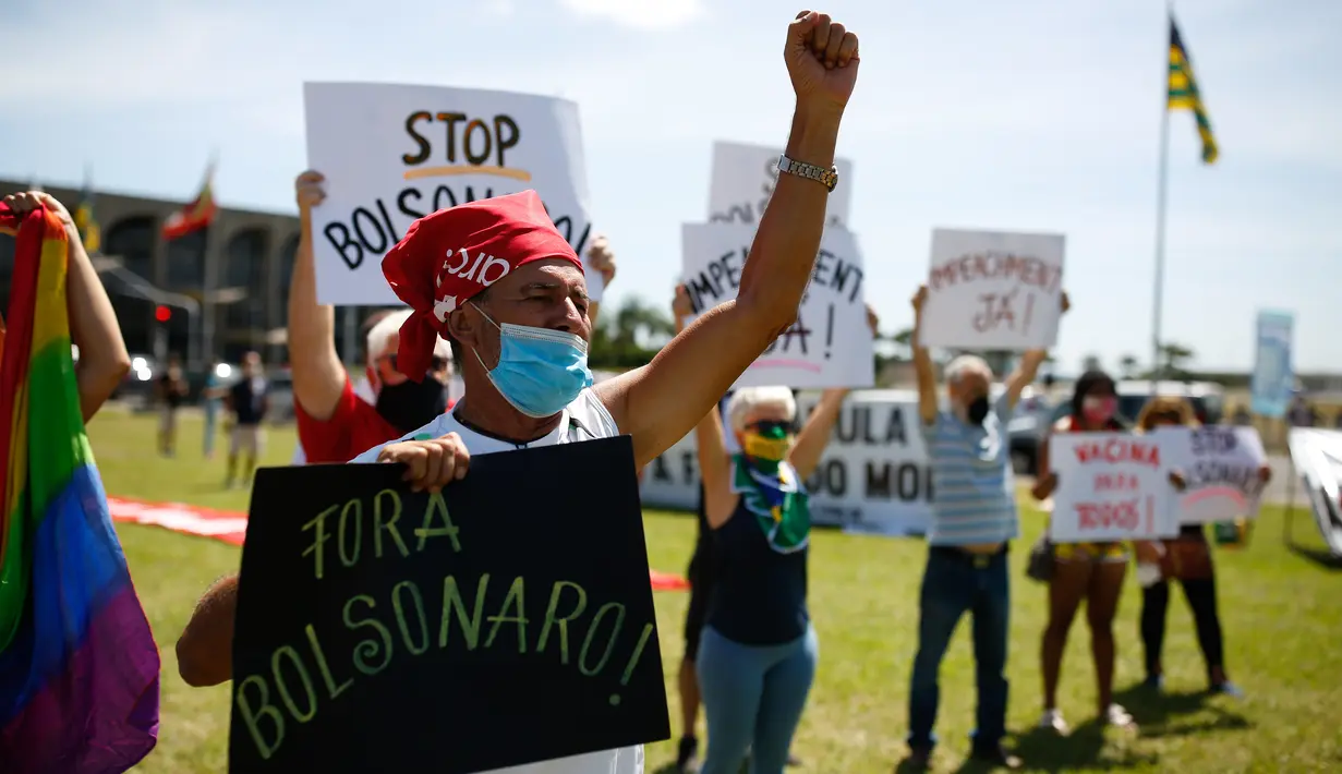 Demonstran membawa poster tuntutan saat memprotes Presiden Brasil Jair Bolsonaro dan penanganan virus corona di Brasilia, Minggu (31/1/2021). Covid-19 merenggut lebih dari 223.000 nyawa menjadikan Brasil sebagai negara dengan jumlah kematian terbanyak kedua di dunia. (Sergio LIMA/AFP)