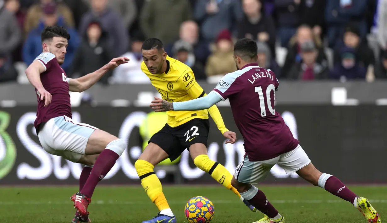 Gelandang Chelsea, Hakim Ziyech berusaha melewati dua pemain West Ham United, Declan Rice dan Manuel Lanzini pada pertandingan lanjutan Liga Inggris di stadion London di London Timur (4/12/2021). West Ham menang atas Chelsea dengan skor 3-2. (AP Photo/Alastair Grant )