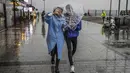 Sepasang warga berlindung dari hujan lebat dengan payung selama hari badai di Istanbul, Turki, Senin (29/11/2021). Badai kuat melanda Istanbul dan bagian lain dari Turki pada hari Senin, menewaskan sedikitnya empat orang dan menyebabkan kekacauan di kota 15 juta orang, menurut laporan. (AP Photo)