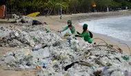 Pekerja mengumpulkan sampah plastik saat membersihkan pantai Kuta dekat Denpasar di pulau wisata Bali (6/1/2021). Pada 1 Januari 2021, sekira 30 ton sampah diangkut dari kawasan Pantai Kuta dalam kegiatan bersih-bersih pantai. (AFP/Sonny Tumbelaka)