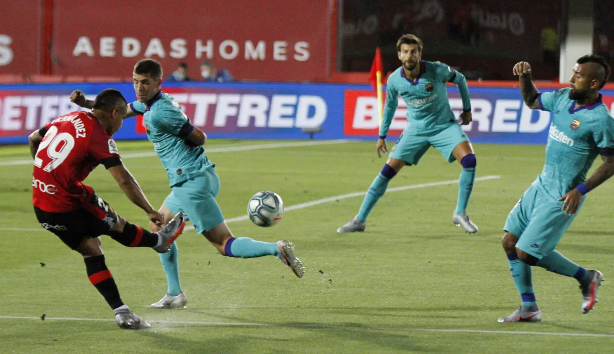 Pemain Marllorca Cucho (kiri) menendang bola saat melawan Barcelona pada pertandingan La Liga di Son Moix Stadium, Palma de Mallorca, Spanyol, Sabtu (13/6/2020). Barcelona membantai Mallorca dengan skor 4-0. (AP Photo/Francisco Ubilla)