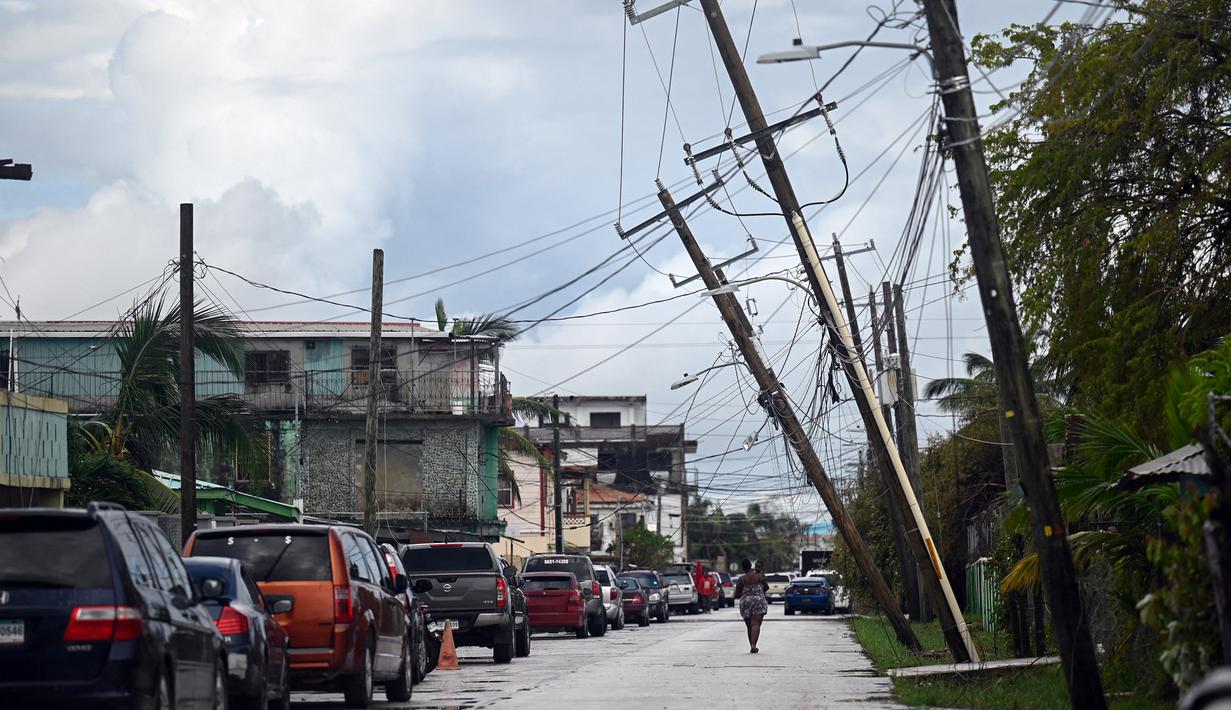 Seorang wanita berjalan melalui jalan setelah Badai Lisa di Belize City, Belize, 3 November 2022. Badai Tropis Lisa menyebabkan banjir dan membuat sebagian negara itu menjadi gelap gulita. (Johan ORDONEZ/AFP)