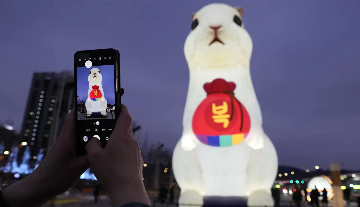 <p>Seorang pengunjung mengambil foto lentera raksasa saat perayaan Tahun Kelinci 2023 mendatang di Lapangan Gwanghwamun, Seoul, Korea Selatan, Senin (19/12/2022). Festival Lentera ini akan berlangsung dari 19-31 Desember 2022. (AP Photo/Ahn Young-joon)</p>