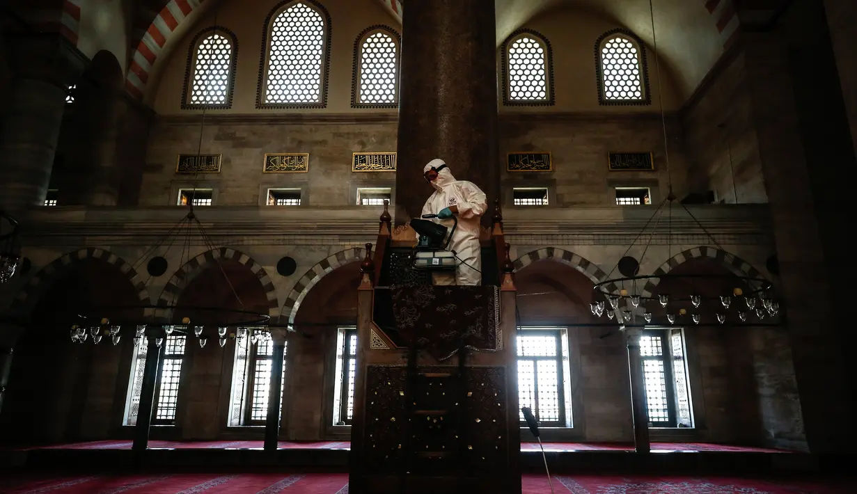 Pekerja mengenakan pakaian pelindung menyemprotkan disinfektan bagian dalam Masjid Suleymaniye yang bersejarah pada hari ketiga Idul Fitri di Istanbul, Selasa (26/5/2020). Beberapa masjid didisinfektan sebelum dibuka kembali pada 29 Mei usai ditutup selama lebih dari enam minggu. (AP/Emrah Gurel)