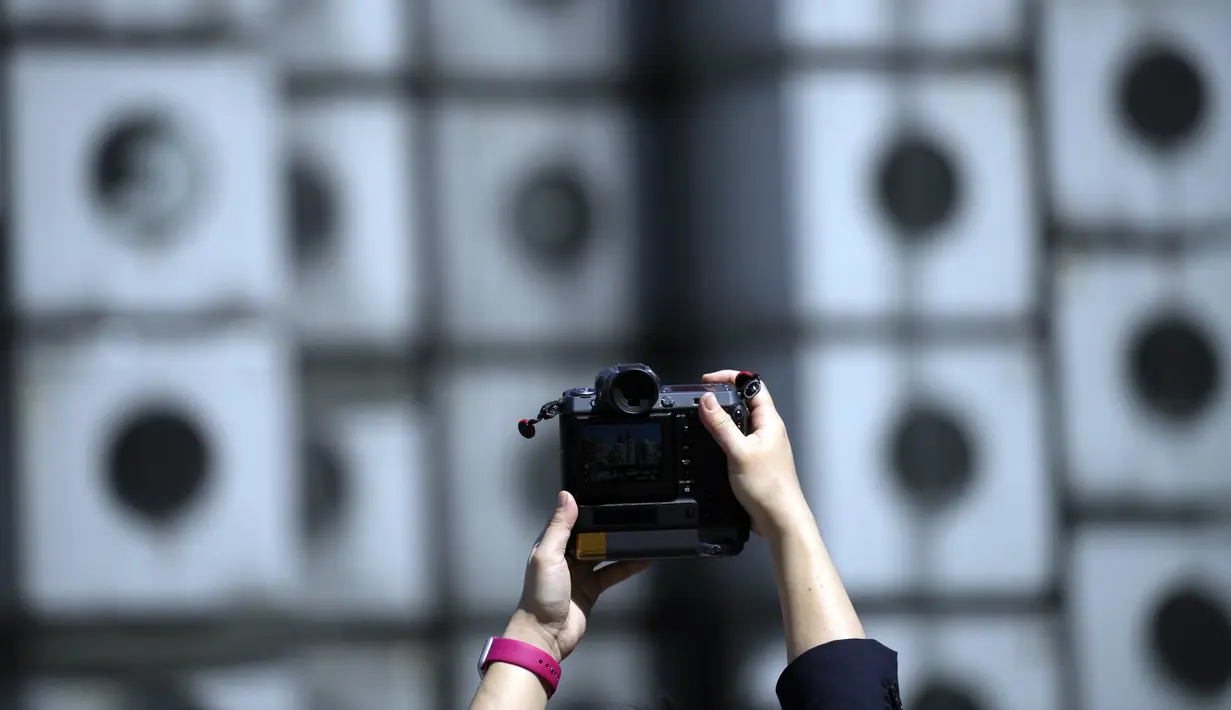 Seorang pria mengambil foto lokasi pembongkaran Nakagin Capsule Tower, bangunan ikonik yang dirancang arsitek Jepang Kisho Kurokawa pada tahun 1972, di distrik Ginza Tokyo, Selasa (12/4/2022). Pekerjaan pembongkaran menara 140 unit kapsul tersebut dimulai Selasa. (AP Photo/Eugene Hoshiko)