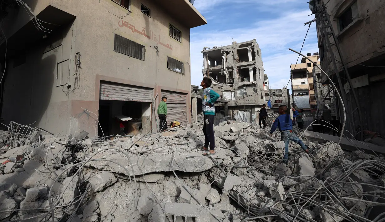 Anak-anak Palestina berjalan di tengah reruntuhan bangunan yang hancur akibat serangan Israel di kamp pengungsi Bureij di Jalur Gaza bagian tengah pada 27 April 2025. (Eyad BABA/AFP)