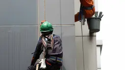 Dua pekerja membersihkan kaca gedung bertingkat di Jakarta, Senin (25/8/2015). Untuk meminimkan kecelakaan, Kementerian Tenaga Kerja dan Transmigrasi telah mencanangkan bulan Keselamatan dan Kesehatan Kerja (K3) pada 2014. (Liputan6.com/Helmi Afandi)