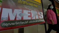 Seorang wanita Thailand berjalan memakai masker melewati pengumuman wabah MERS di Nonthaburi, Thailand, (19/6/2015). Pemerintah Thailand mengumumkan bahwa seorang pria 75 tahun asal Oman positif terjangkit virus MERS. (AFP PHOTO/Pornchai KITTIWONGSAKUL)