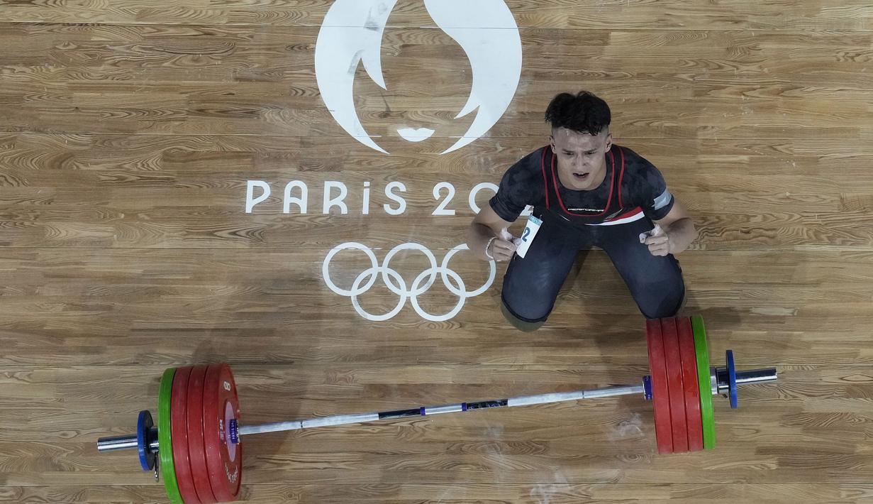 Selebrasi atlet angkat besi Indonesia, Rizki Juniansyah setelah berhasil mengangkat beban seberat 199 kg pada angkatan clean and jerk sekaligus memastikan merebut medali emas saat berlomba pada kelas 73 kg putra cabor angkat besi Olimpiade Paris 2024 di Paris Expo Porte de Versailles, Paris, Kamis (8/8/2024). (AP Photo/Dita Alangkara)