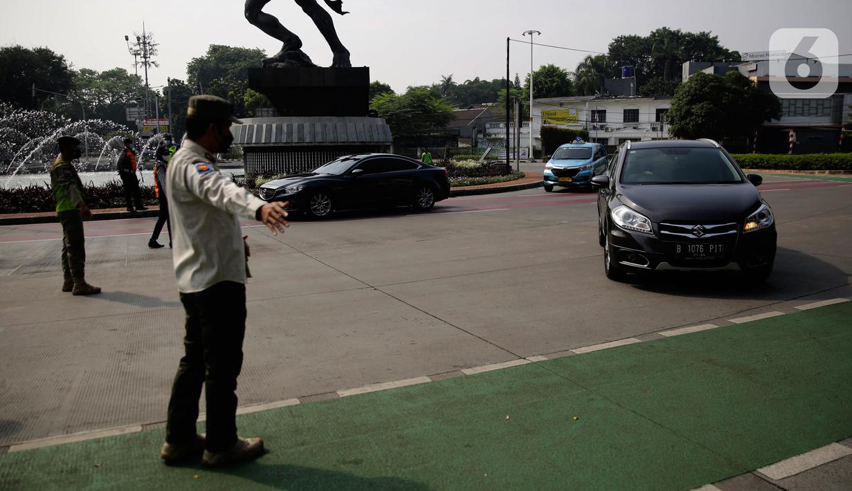 Petugas polisi mengarahkan kendaraan berplat nomor genap di pos penyekatan ganjil-genap di Bundaran Senayan, Minggu (5/9/2021). Pembatasan kendaraan dengan sistem pelat nomor kendaraan ini tetap berlaku di akhir pekan, Sabtu dan Minggu. (Liputan6.com/Angga Yuniar)