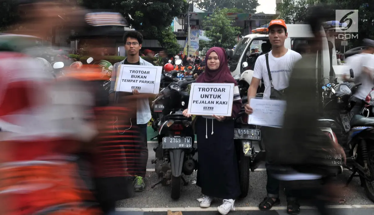 Koalisi Pejalan Kaki membawa poster saat menggelar aksi Tamasya Trotoar Kita di lokasi parkir liar sepanjang jalur pedestrian Gelora Bung Karno (GBK), Jakarta, Minggu (9/12). (Merdeka.com/Iqbal S. Nugroho)