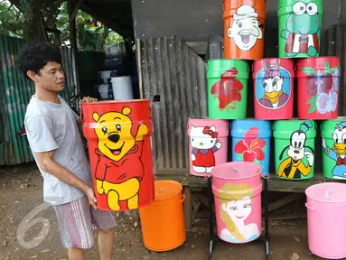 Seorang pengrajin lukis tong sampah membawa hasil karyanya yang siap dijual di kawasan serpong, Tangerang Selatan, Senin (20/3). Tong sampah bermotif karakter kartun tersebut di jual seharga 80-125 ribu. (Liputan6.com/Helmi Afandi)