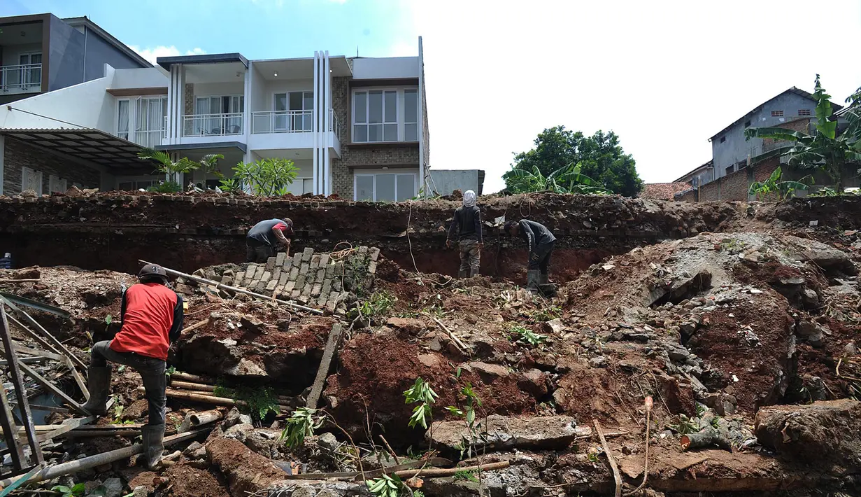 Pekerja membenahi material tembok perumahan Lereng Indah yang longsor dan menimpa kendaraan di Perumahan Lereng Bukit Indah, Pondok Cabe Udik, Pamulang,Tangerang Selatan, Senin (8/4). Dua mobil warga perumahan Lereng Indah rusak tertimpa longsor saat hujan deras. (merdeka.com/Arie Basuki)