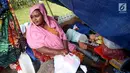 Seorang wanita pencari suaka termenung di samping anaknya yang tertidur di trotoar depan Rumah Detensi Imigrasi Kalideres, Jakarta, Jumat (19/1). Para pencari suaka berasal dari Afghanistan, Sudan, dan Somalia. (Liputan6.com/JohanTallo)