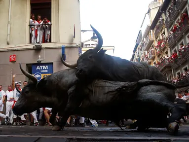 Dua banteng terjatuh saat ingin menyeruduk peserta pada festival San Fermin di Pamplona, Spanyol utara, (9/7). festival tahunan ini amat populer di Spanyol, dimana peserta diuji Keberaniannya dalam berhadapan dengan banteng. (REUTERS/Eloy Alonso)