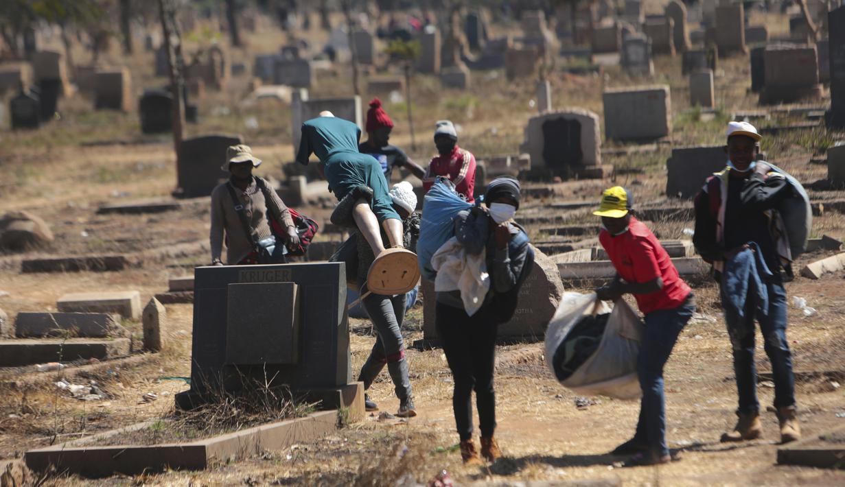 Pedagang Zimbabwe membawa dagangannya di kuburan setelah kabur dari kejaran polisi yang mengejar mereka setelah kedapatan berjualan dari tempat yang tidak ditentukan karena pembatasan COVID-19 di Harare, Kamis (29/7/2021). (AP Photo/Tsvangirayi Mukwazhi)