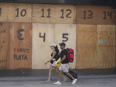 Orang-orang berjalan melewati etalase toko suvenir yang dipasangi papan persiapan kedatangan Badai Beryl, di Playa del Carmen, Meksiko, Kamis (4/7/2024). (AP Photo/Fernando Llano)