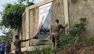 Anggota Satpol PP Kota Depok saat menurunkan spanduk Sekda Kota Depok, Supian Suri saat kegiatan ngubek Empang di Cilodong, Depok. (Istimewa)